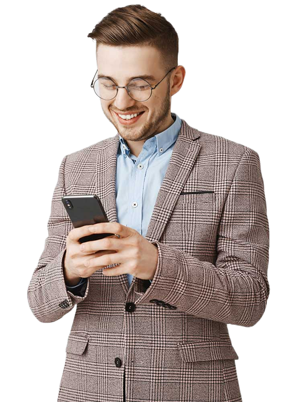 A young man in a checked blazer and glasses smiling while using a smartphone.