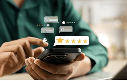 A close-up image of a person using a smartphone, with floating review stars and text bubbles above the phone screen. The person is interacting with a review system, with multiple star ratings (5.0, 3.5, 4.0) appearing in the air above the phone.